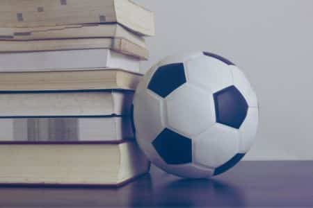 Soccer ball next to stack of books.