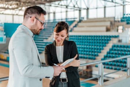 people discussing notes with a basketball court in the back.