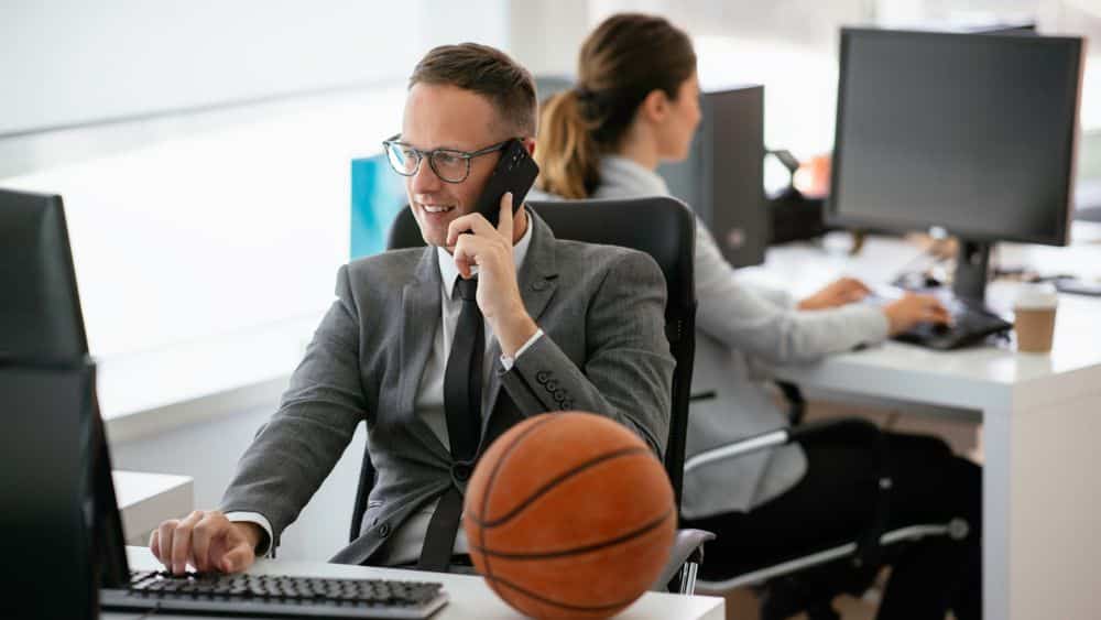 Sports professional talking on phone in office with basketball