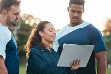 Sports team members reviewing clipboard during outdoor training