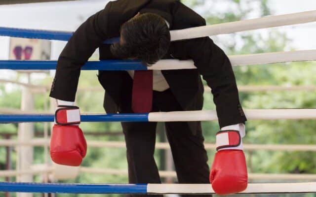 businessman defeated in a boxing ring.