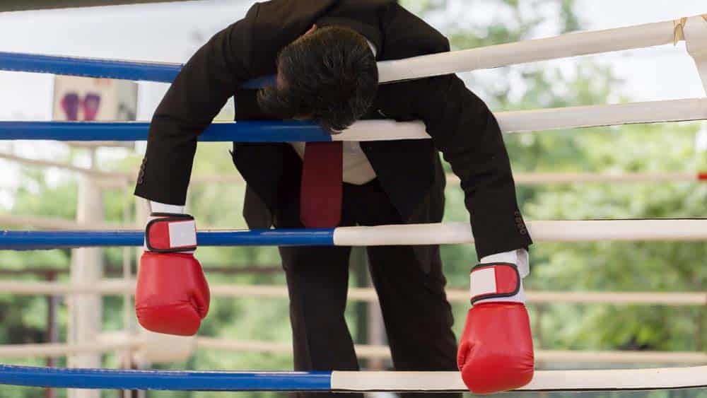 businessman defeated in a boxing ring.