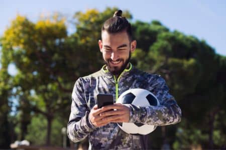 Man writing on his phone after a soccer match.