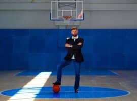 basketball professional standing on a court in business attire
