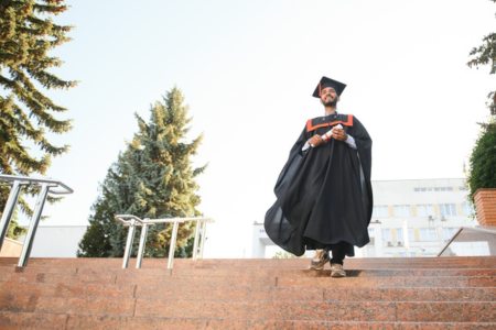 A master's student in graduation garb walking down stairs