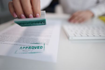 Document being stamped with green approval stamp