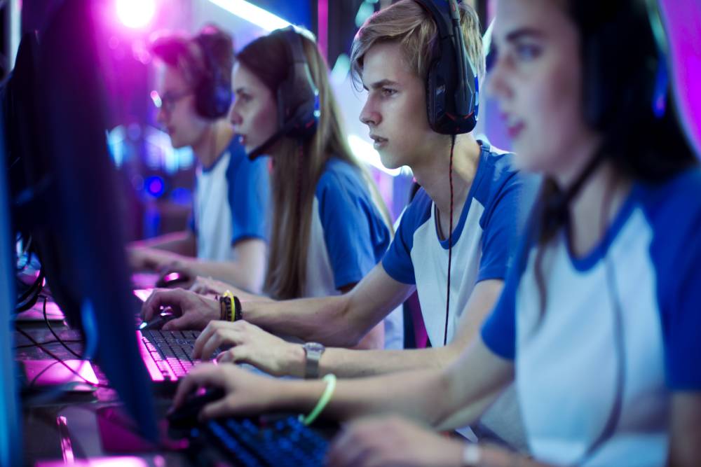 A team of esport athletes play on computers with focus to win the game.