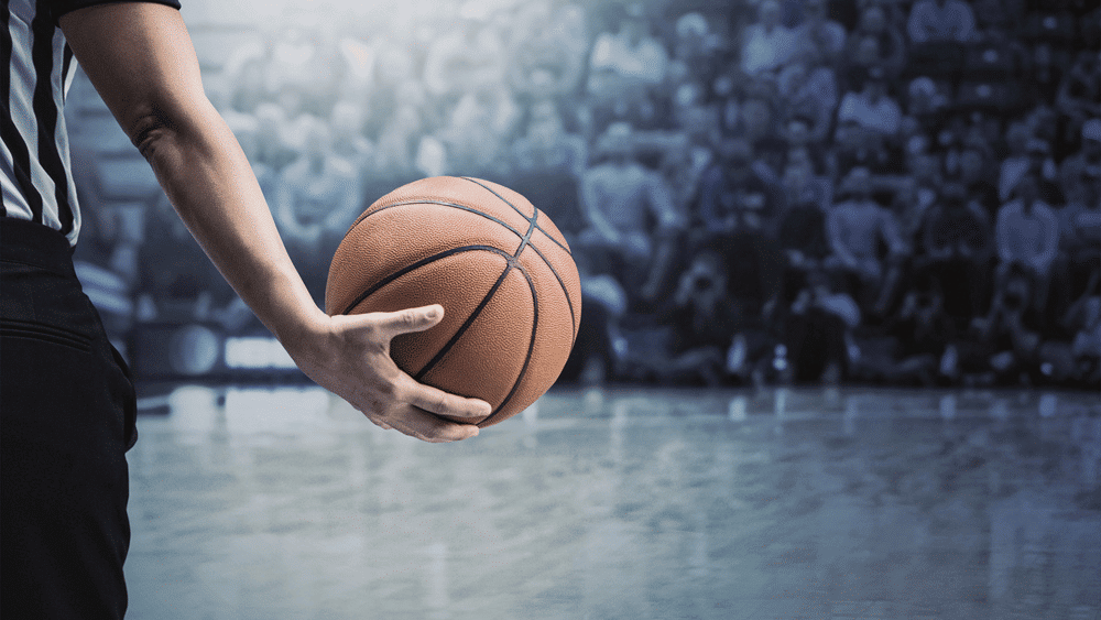 An NBA referee holding a basketball in front of a crowd