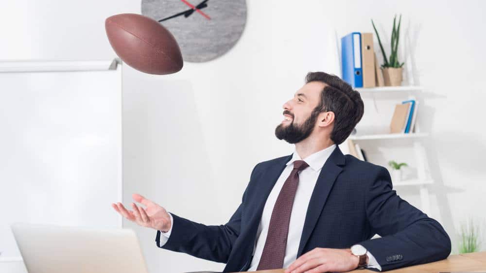 Office worker with a football thinking about Super Bowl jobs