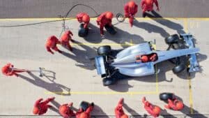 An indy car leaving a pit stop shown from above