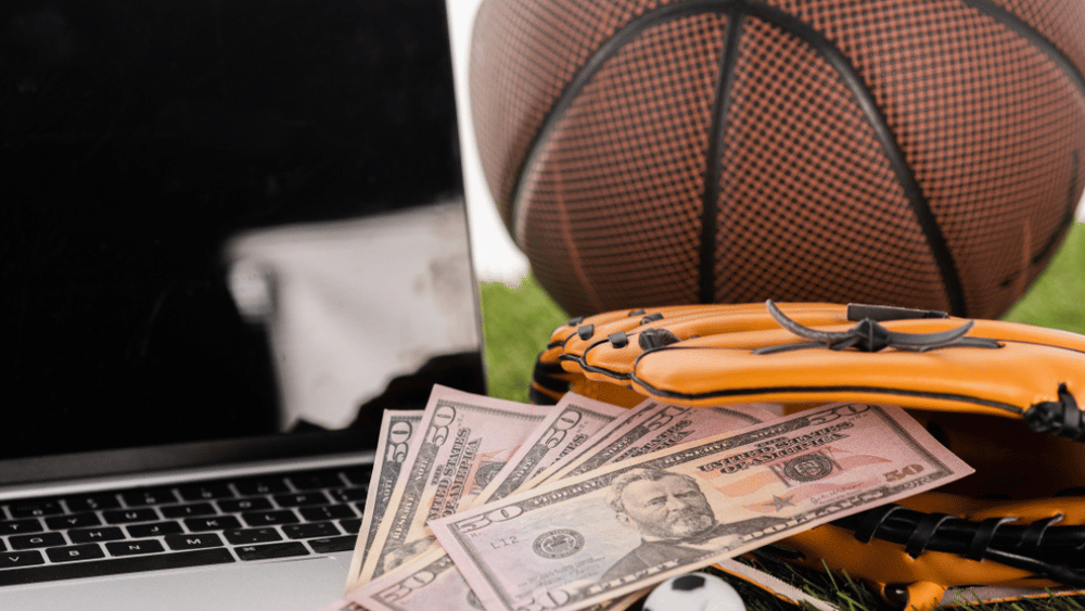 A basketball and a baseball glove sitting next to 50-dollar bills