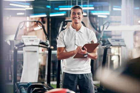 Smiling student with clipboard learning how to become an NFL athletic trainer