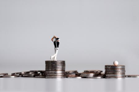 A golfer figurine sitting on top of a stack of coins