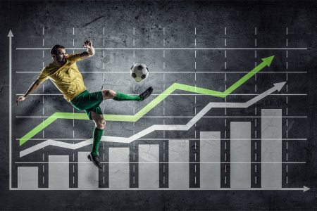 Soccer player kicking a soccer ball in front of a graph with rising lines and bars.