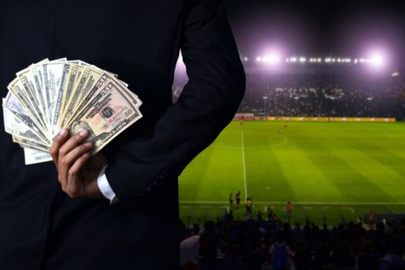 A soccer scout holding money behind their back