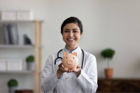 A smiling nurse holding a piggy bank