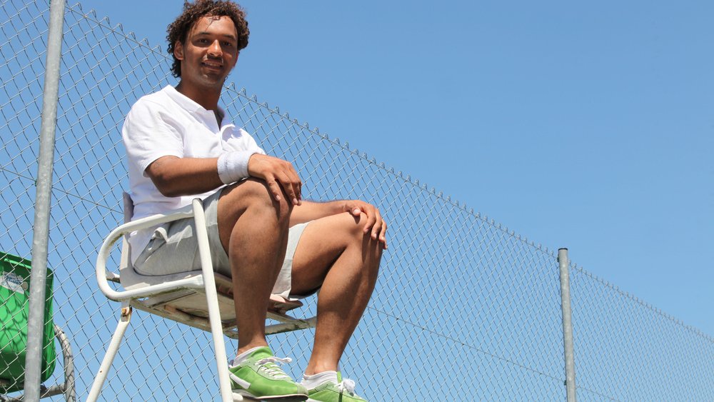 Happy tennis umpire sitting on a chair