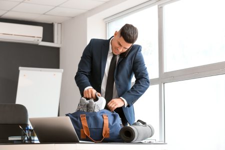 Young businessman packing shoes into a sports bag.