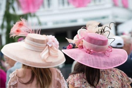 wo people at the Kentucky Derby wearing elegant hats made by a milliner