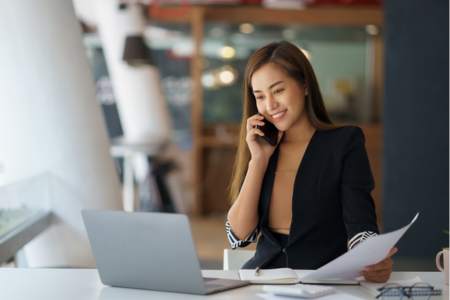 A smiling public relations assistant smiling while on the phone