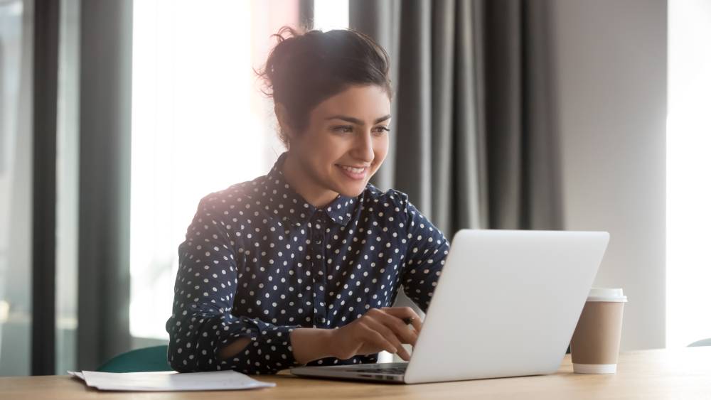 A social media specialist works at her laptop on new content for a social media campaign.