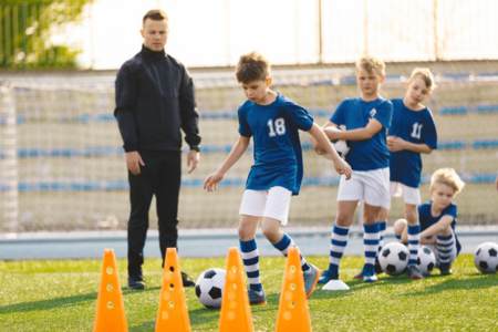 A sports camp coordinator assistant teaching kids to play soccer