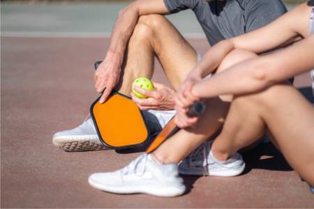 A pickleball instructor talking with a student on the pickleball court
