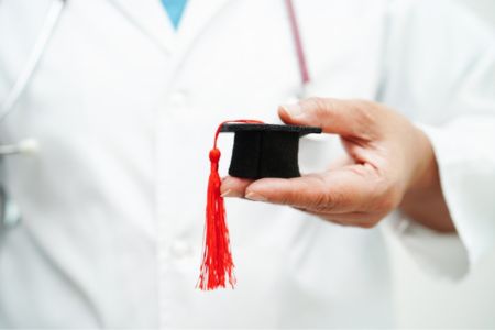 A doctor holding a miniature graduation cap