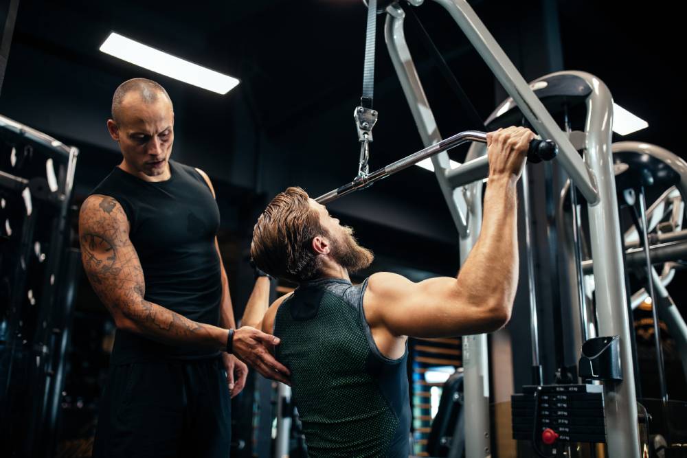 A strength and conditioning coach helps a player with a workout