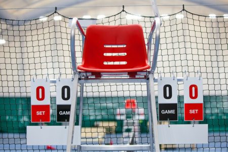 A tennis umpire chair sitting next to scoring cards