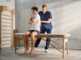 An injury prevention specialist assisting an athlete on an exam table.