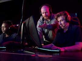 An esports coach guiding an esports team player gaming on a desktop computer.