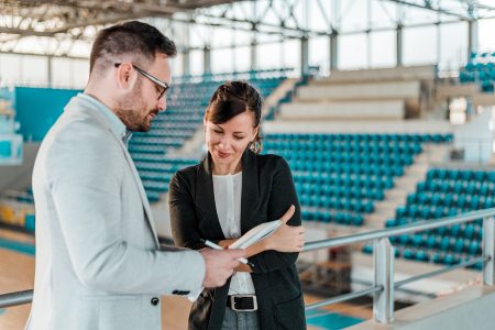 A sports marketer sharing information with a brand representative in a basketball court.