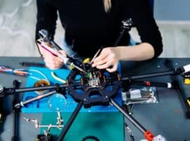 A sports engineer building a racing drone on a table.