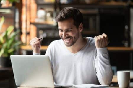 An excited man with a computer is receiving good news after the interview.