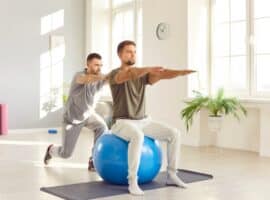 An exercise physiologist assists an athlete in performing an exercise.