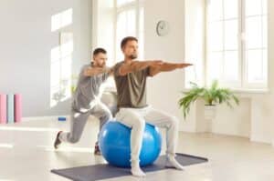 An exercise physiologist assists an athlete in performing an exercise.