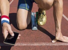 Man on running track checking social media.