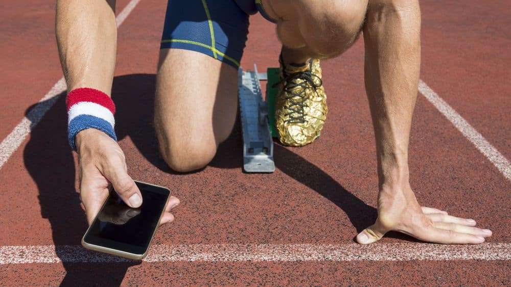 Man on running track checking social media.