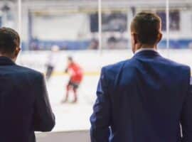suited men watching a hockey game