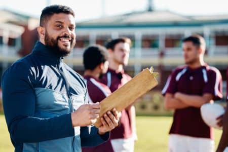sports manager looking at the camera with players behind him.