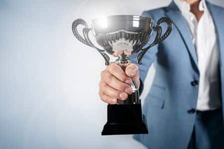 suited woman holding a small trophy.