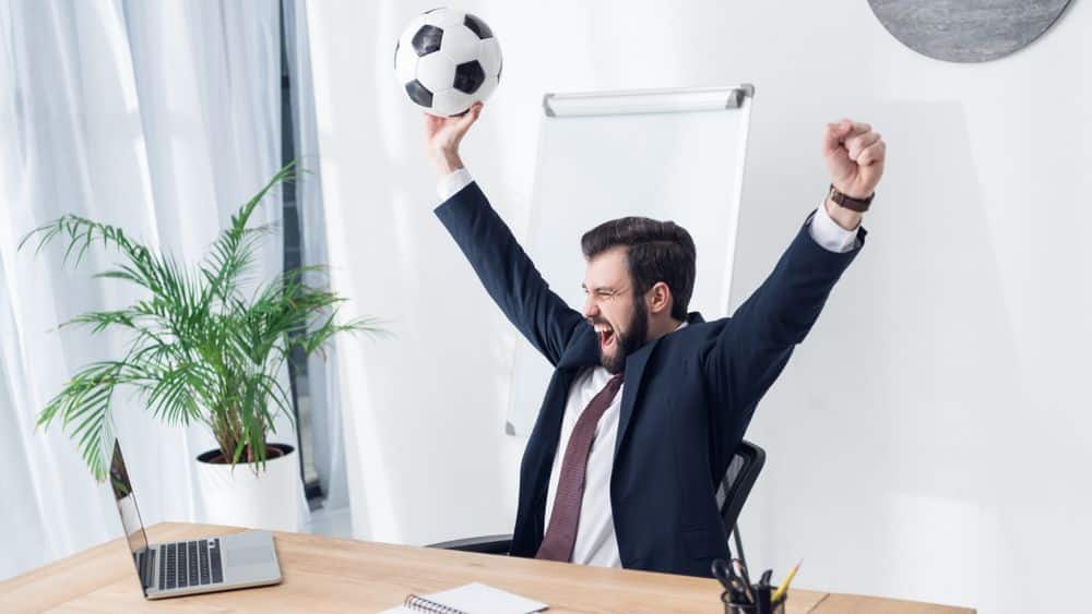 businessman in an office celebrating with a soccer ball.