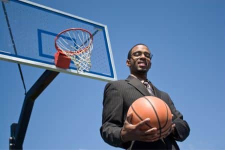 suited man posing with a basketball.