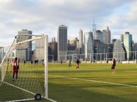 soccer players competing with a city skyline in the background