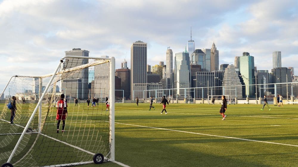 soccer players competing with a city skyline in the background