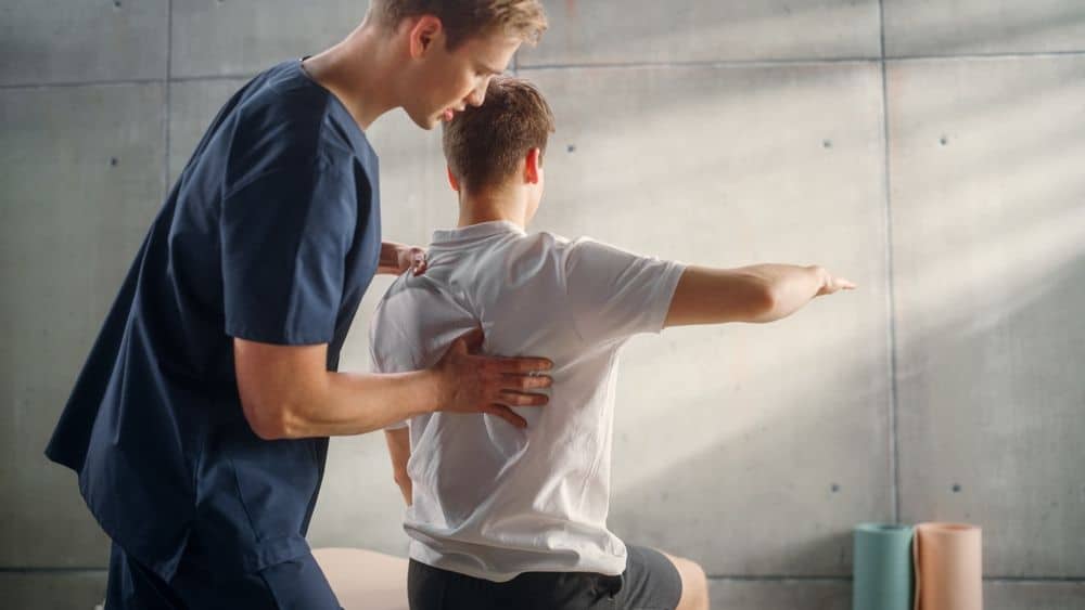 A nurse assisting an athlete with their back.