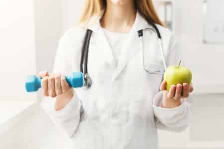 Dietitian holding a dumbbell and an apple.