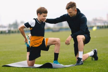 Soccer trainer assisting a young player's training.