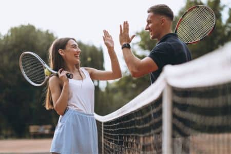 A tennis trainer congratulating an athlete.